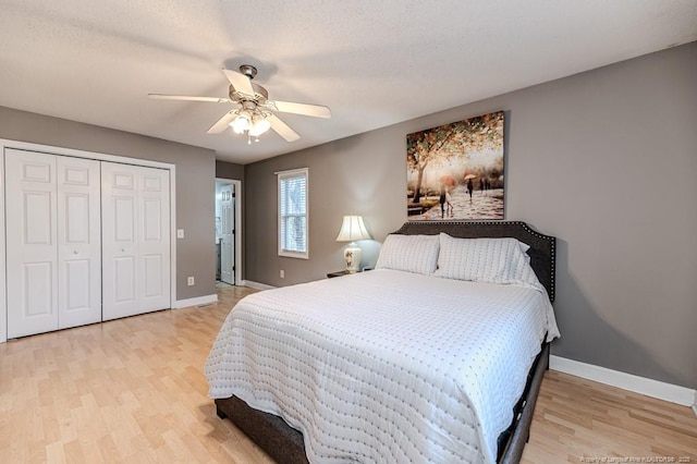 bedroom with light wood-style floors, a closet, ceiling fan, and baseboards