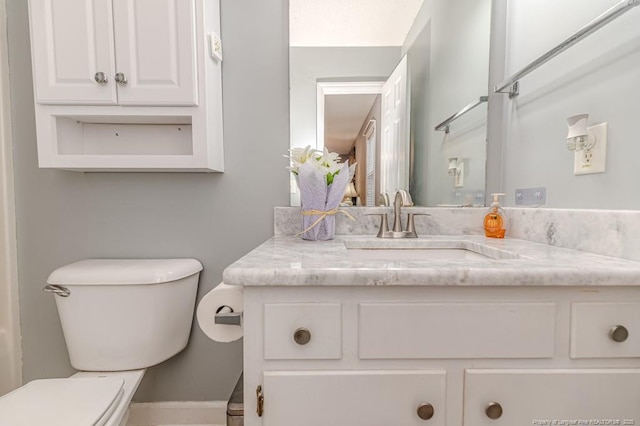 bathroom with baseboards, vanity, and toilet