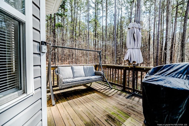 wooden deck with a forest view and outdoor lounge area