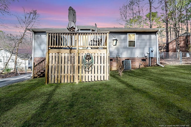 back of house at dusk with central AC unit, a lawn, stairs, fence, and a wooden deck