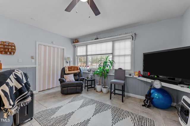 living area with heating unit, a wainscoted wall, and ceiling fan