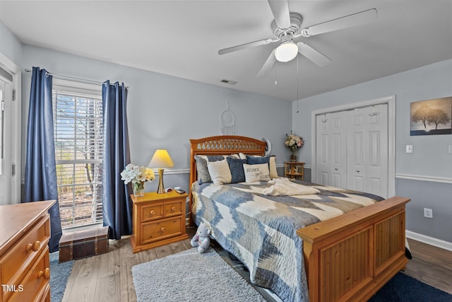 bedroom featuring baseboards, visible vents, a ceiling fan, wood finished floors, and a closet