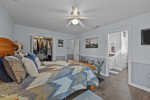 bedroom with a closet, visible vents, a spacious closet, wood finished floors, and baseboards