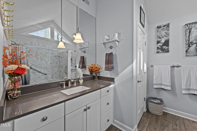 bathroom with baseboards, visible vents, wood finished floors, vaulted ceiling, and vanity