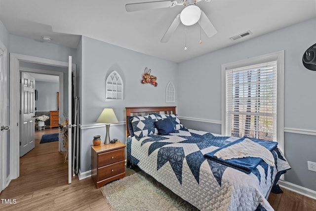 bedroom featuring a ceiling fan, baseboards, visible vents, and wood finished floors