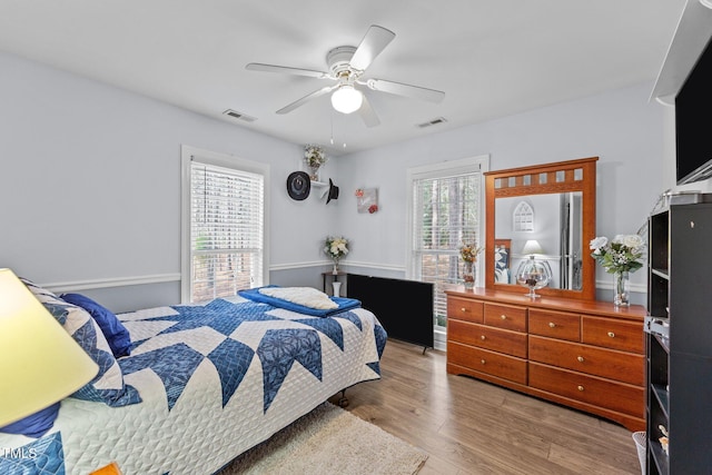 bedroom featuring wood finished floors, visible vents, and a ceiling fan