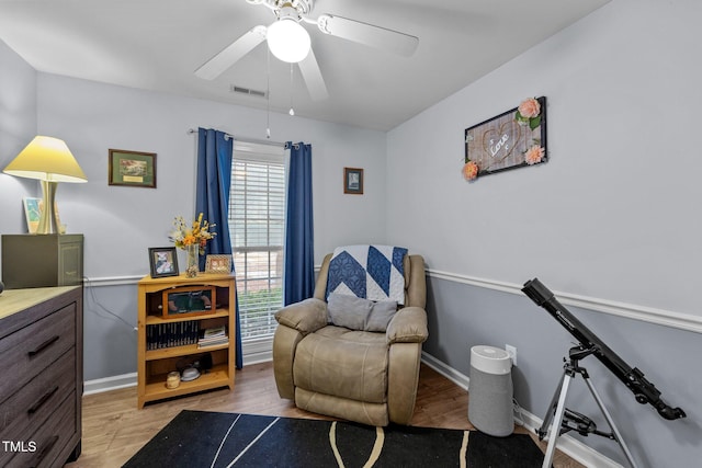 sitting room featuring a ceiling fan, visible vents, light wood-style flooring, and baseboards