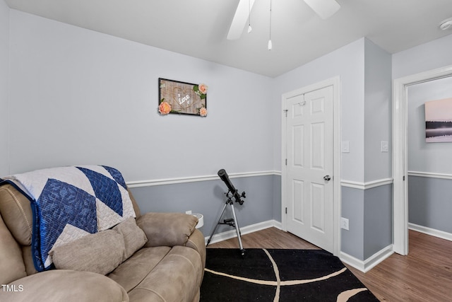 living area featuring a ceiling fan, baseboards, and wood finished floors