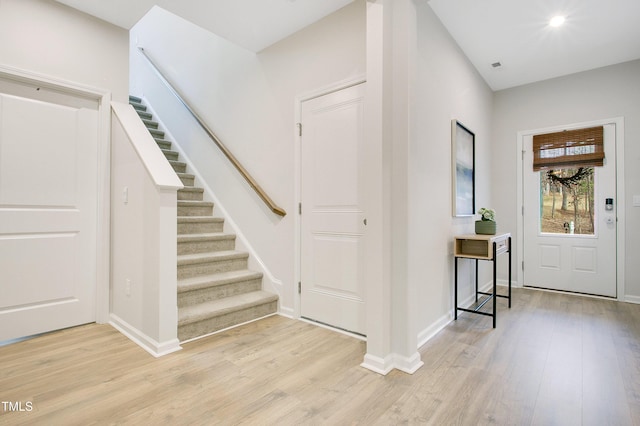 entryway with stairway, baseboards, and light wood finished floors