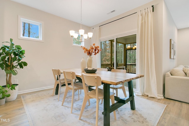 dining space with a healthy amount of sunlight, visible vents, a chandelier, and light wood-type flooring