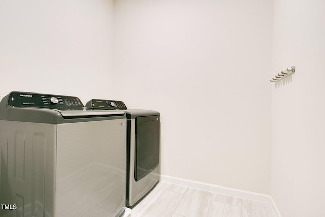 washroom with laundry area, washing machine and dryer, and baseboards