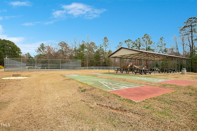 view of community with a tennis court, shuffleboard, and fence