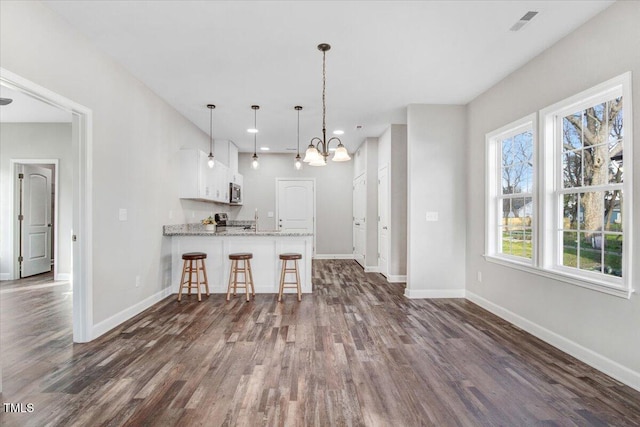 kitchen with dark wood-style floors, baseboards, white cabinets, and a notable chandelier