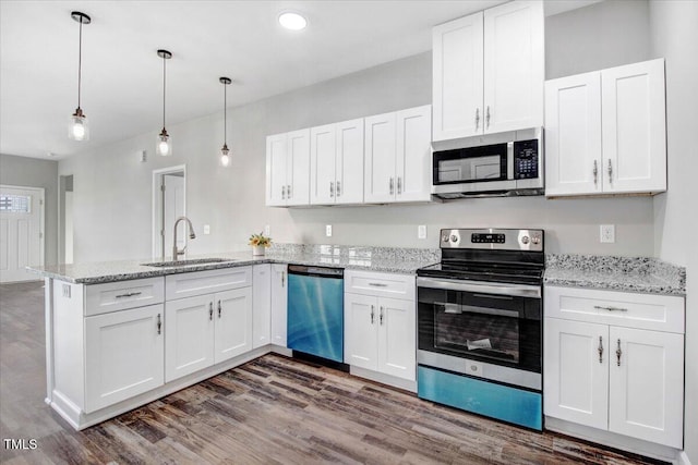 kitchen with a peninsula, appliances with stainless steel finishes, a sink, and white cabinetry