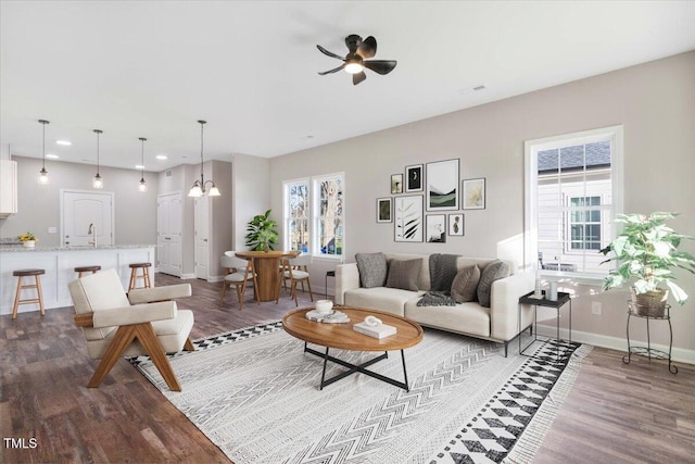 living room with dark wood finished floors, recessed lighting, visible vents, baseboards, and ceiling fan with notable chandelier