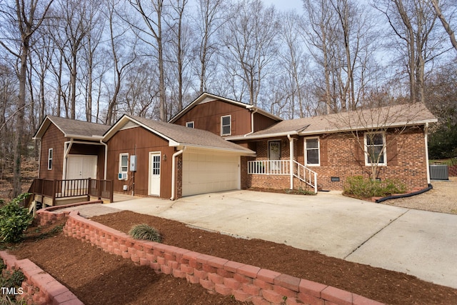 tri-level home with brick siding, concrete driveway, central AC unit, and a garage