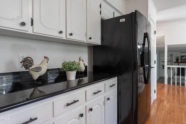 kitchen featuring white cabinetry, dark countertops, light wood-type flooring, and black refrigerator with ice dispenser