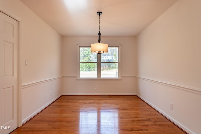 spare room with baseboards and wood finished floors