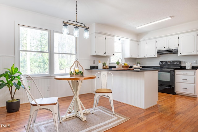 kitchen with under cabinet range hood, dark countertops, black range with electric cooktop, white cabinetry, and a peninsula