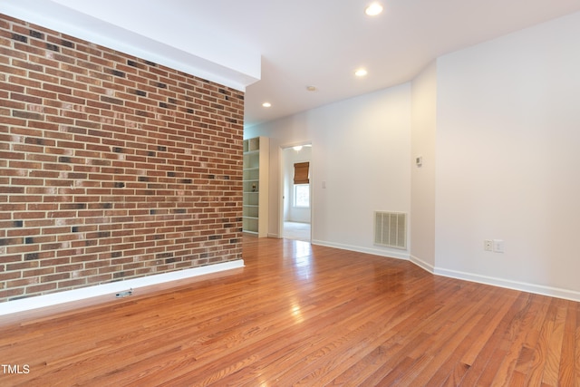 spare room with visible vents, brick wall, baseboards, recessed lighting, and hardwood / wood-style flooring