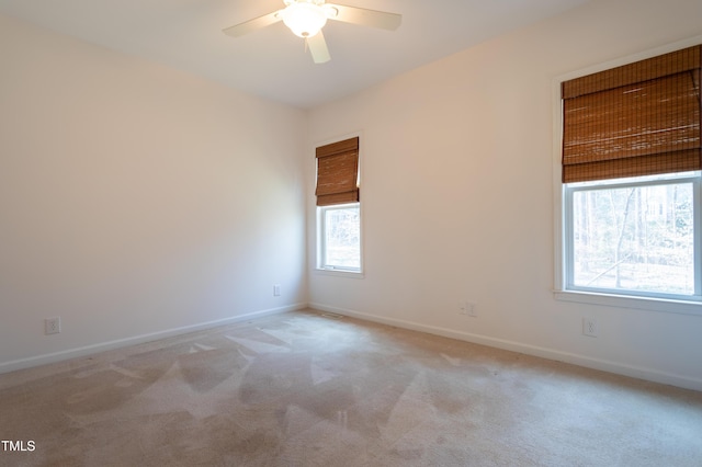 empty room featuring light carpet, baseboards, and ceiling fan