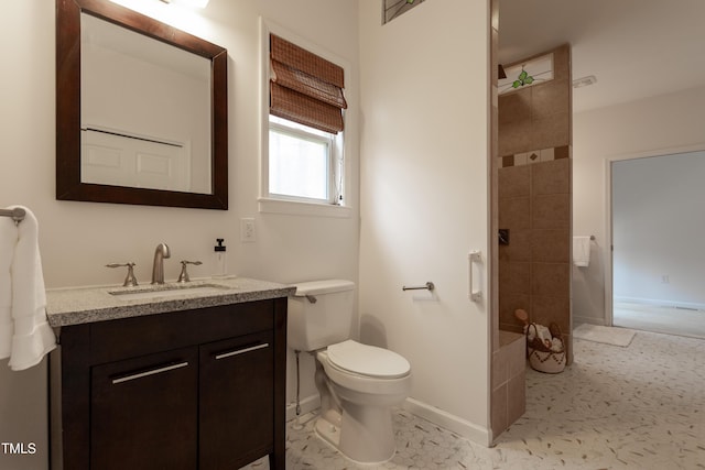 full bathroom featuring baseboards, toilet, vanity, and a tile shower