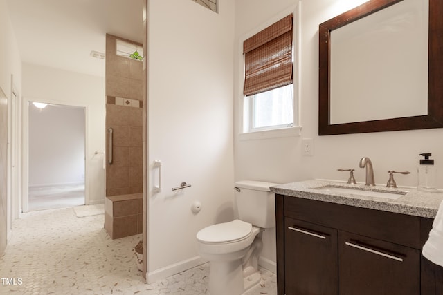 full bath featuring vanity, toilet, baseboards, and a tile shower