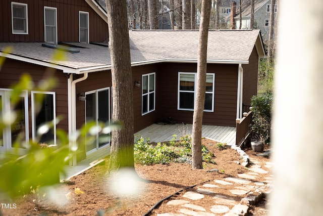 rear view of property featuring roof with shingles and a deck