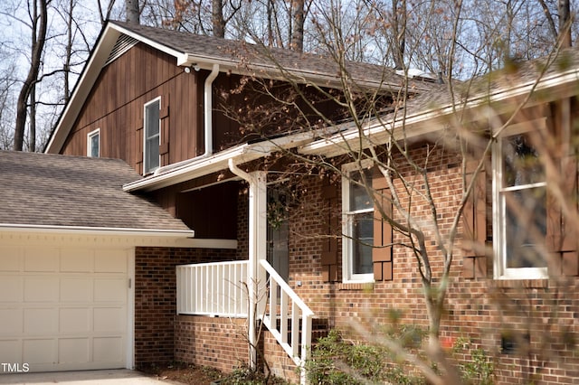 exterior space featuring a garage, brick siding, and a shingled roof