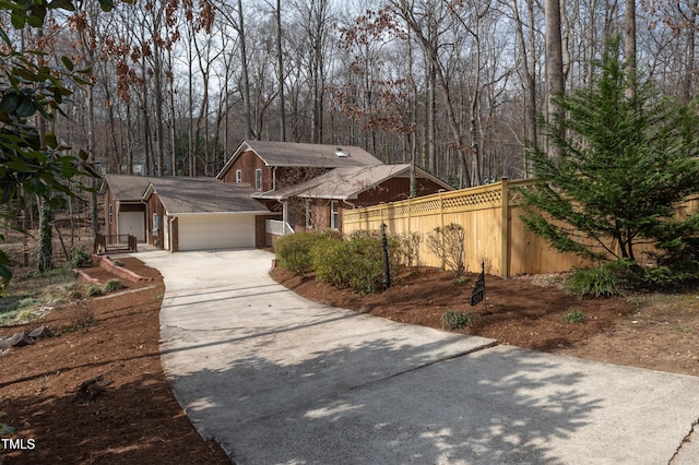 view of front facade featuring driveway, an attached garage, and fence