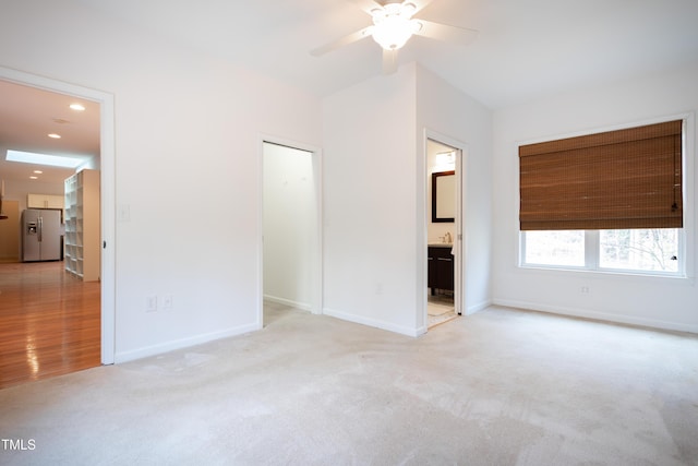 unfurnished bedroom with baseboards, ensuite bath, recessed lighting, carpet flooring, and stainless steel fridge