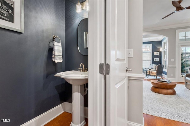 bathroom featuring baseboards, wood finished floors, a ceiling fan, and ornamental molding