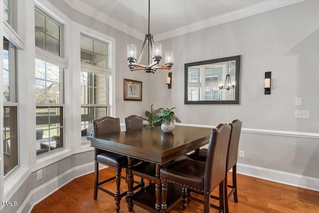 dining space featuring baseboards, a notable chandelier, wood finished floors, and ornamental molding