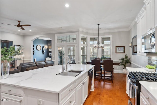 kitchen with crown molding, open floor plan, light wood-style flooring, stainless steel appliances, and a sink