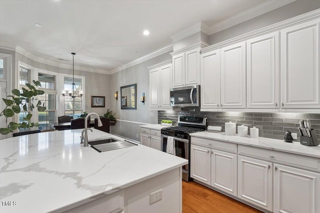 kitchen with a sink, ornamental molding, stainless steel appliances, white cabinets, and tasteful backsplash