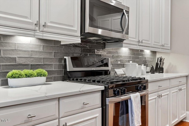 kitchen featuring white cabinetry, decorative backsplash, light stone countertops, and appliances with stainless steel finishes