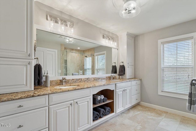 full bath with a sink, baseboards, double vanity, and a shower stall