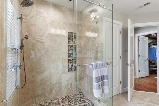 full bathroom with a spacious closet, visible vents, and a shower stall