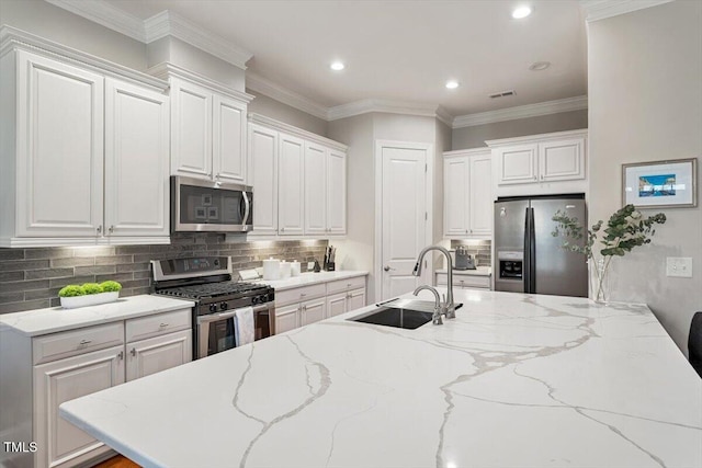 kitchen with decorative backsplash, white cabinets, appliances with stainless steel finishes, and a sink