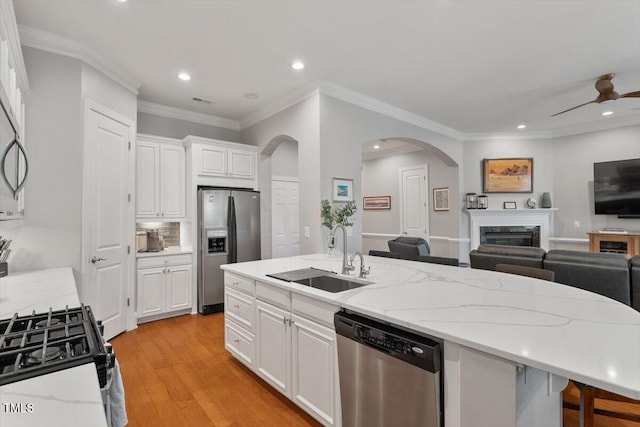 kitchen with light wood finished floors, a sink, stainless steel appliances, white cabinets, and open floor plan