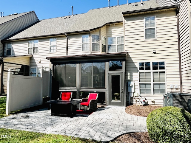 back of house with a shingled roof, fence, a patio, and a sunroom