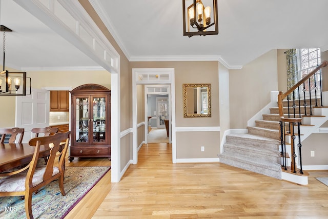 dining room with crown molding, baseboards, stairway, light wood-style floors, and a notable chandelier