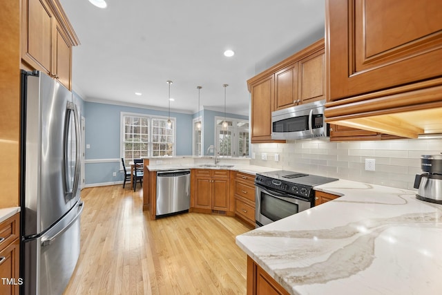 kitchen featuring a peninsula, brown cabinets, appliances with stainless steel finishes, and a sink