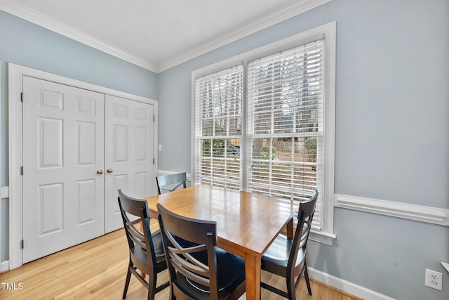 dining area with crown molding, baseboards, and light wood-type flooring