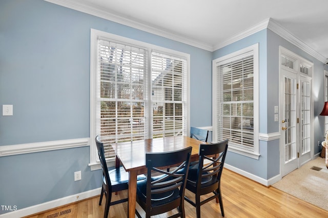 dining area with visible vents, baseboards, wood finished floors, and crown molding