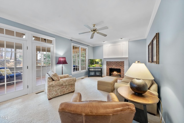 living area with visible vents, a fireplace, carpet flooring, crown molding, and ceiling fan