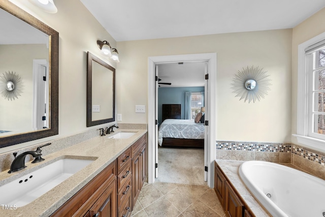 bathroom with double vanity, a tub with jets, ensuite bathroom, and a sink