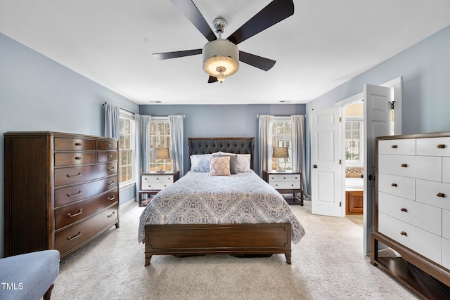 bedroom with a ceiling fan, ensuite bath, and light colored carpet