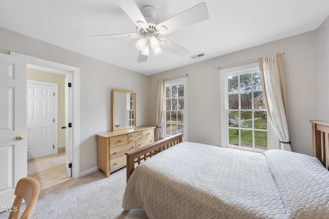 bedroom with visible vents, light carpet, baseboards, and a ceiling fan