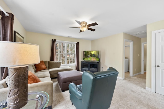 living area with baseboards, visible vents, washer / dryer, ceiling fan, and light carpet